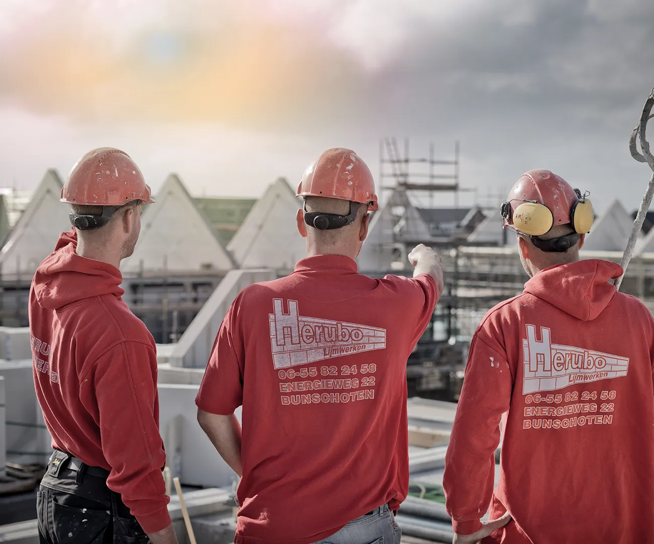 Drie medewerkers van HERUBO die overleggen op een bouwlocatie
